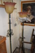 Two similar iron framed standard lamps with peach frilled glass shades