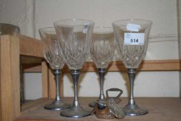 Four wine glasses with metal stems and a novelty bottle opener