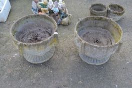 A pair of reconstituted stone planters on pedestals