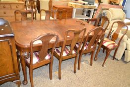 An early 20th Century walnut veneered extending dining table together with a harlequin set of