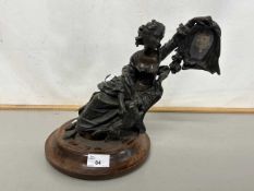 20th Century novelty bronze figure holding aloft a small portrait photograph set on a turned