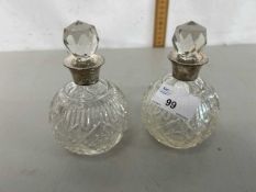 A pair of small cut clear glass and silver collared dressing table bottles
