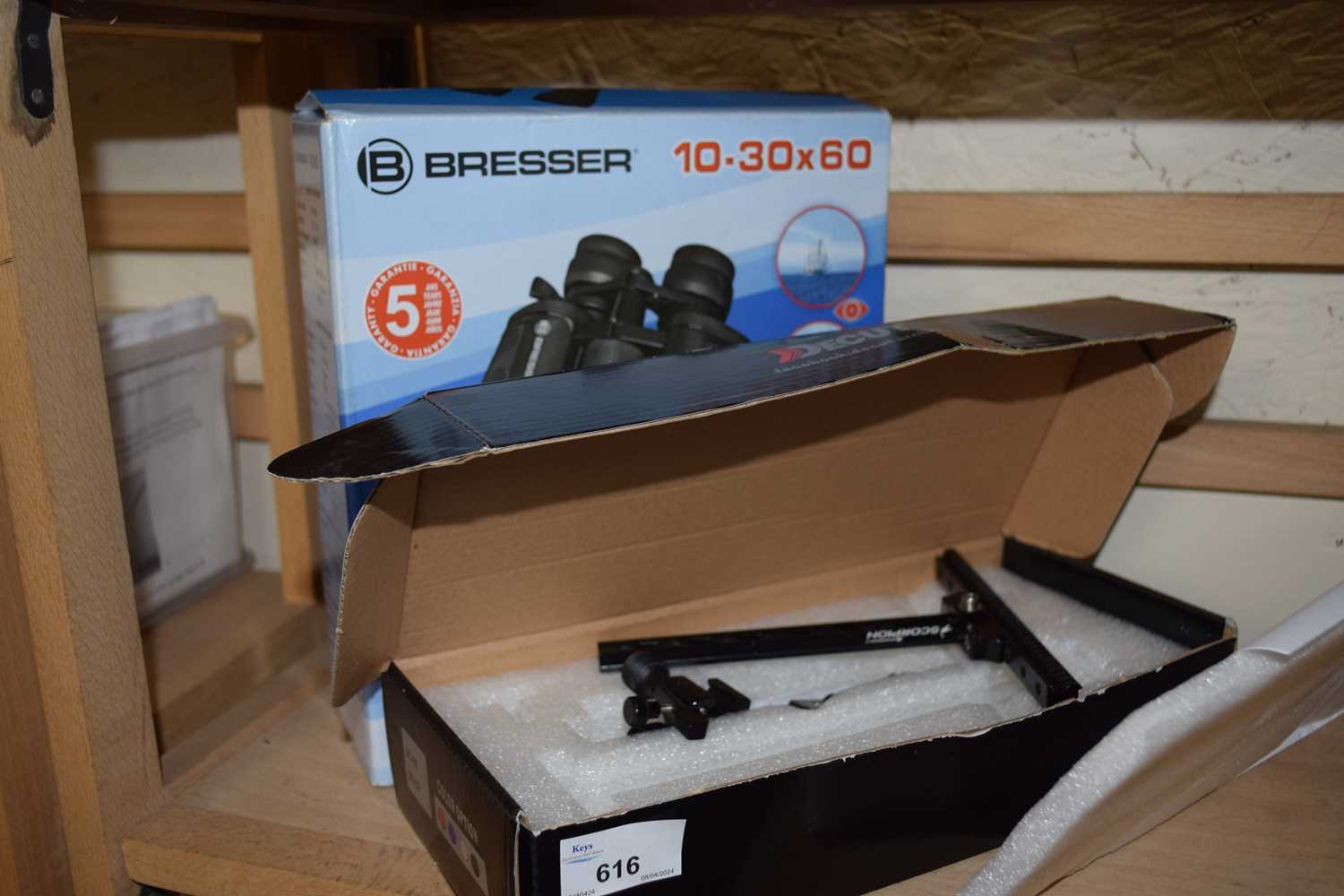 An archery sight, boxed together with a pair of Bresser binoculars, boxed