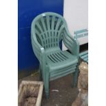 Four green stacking plastic garden chairs