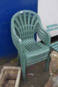 Four green stacking plastic garden chairs