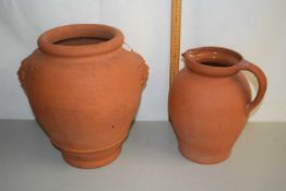 A terracotta ovoid formed jar with mask decoration together with a further terracotta jug (2)