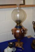 An oil lamp with bulbous copper body and frosted glass shade