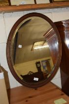 An oval bevelled wall mirror in hardwood frame