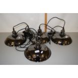 A group of four modern hanging metal pendant light fittings in the industrial style