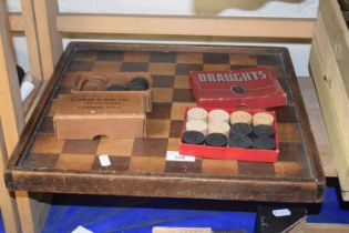 A draughts board and two sets of wooden draughts pieces