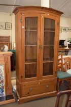 A modern pine glazed bookcase cabinet with drawer base