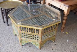 An Indian style octagonal table, highly decorated throughout with carved and guilded and painted