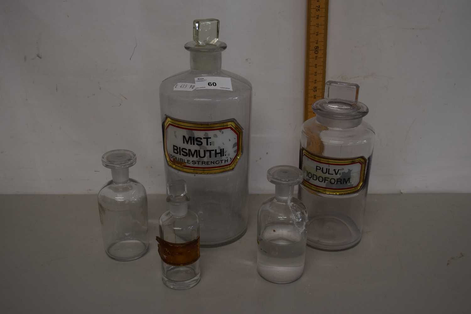 A group of four various clear glass chemists bottles