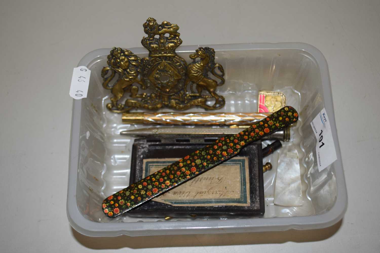 A box containing small brass plaque, various propelling pencils and other items