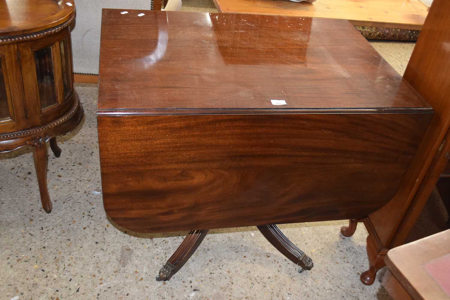 A mahogany single pedestal drop leaf dining table with brass paw feet