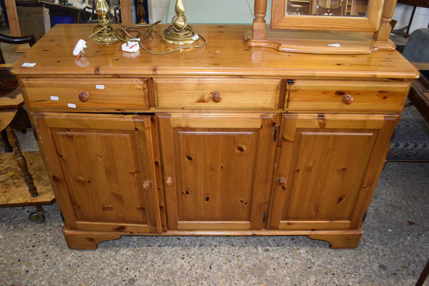 A reproduction pine three door, three drawer sideboard