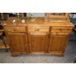 A reproduction pine three door, three drawer sideboard