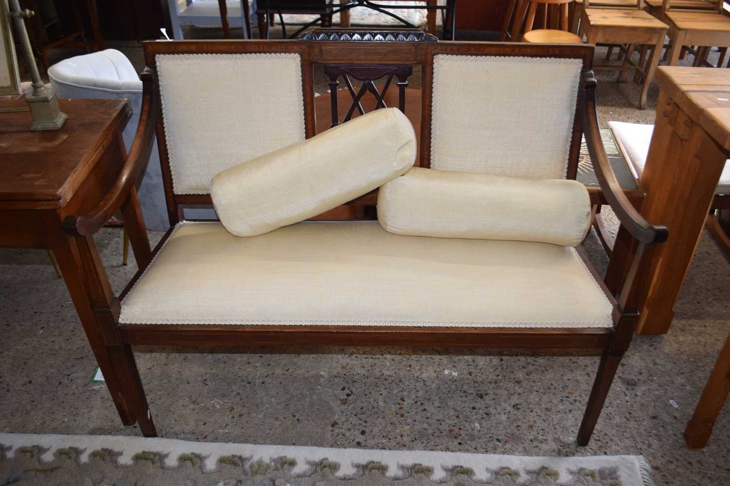 An Edwardian mahogany framed sofa with cream upholstery and bolster cushions