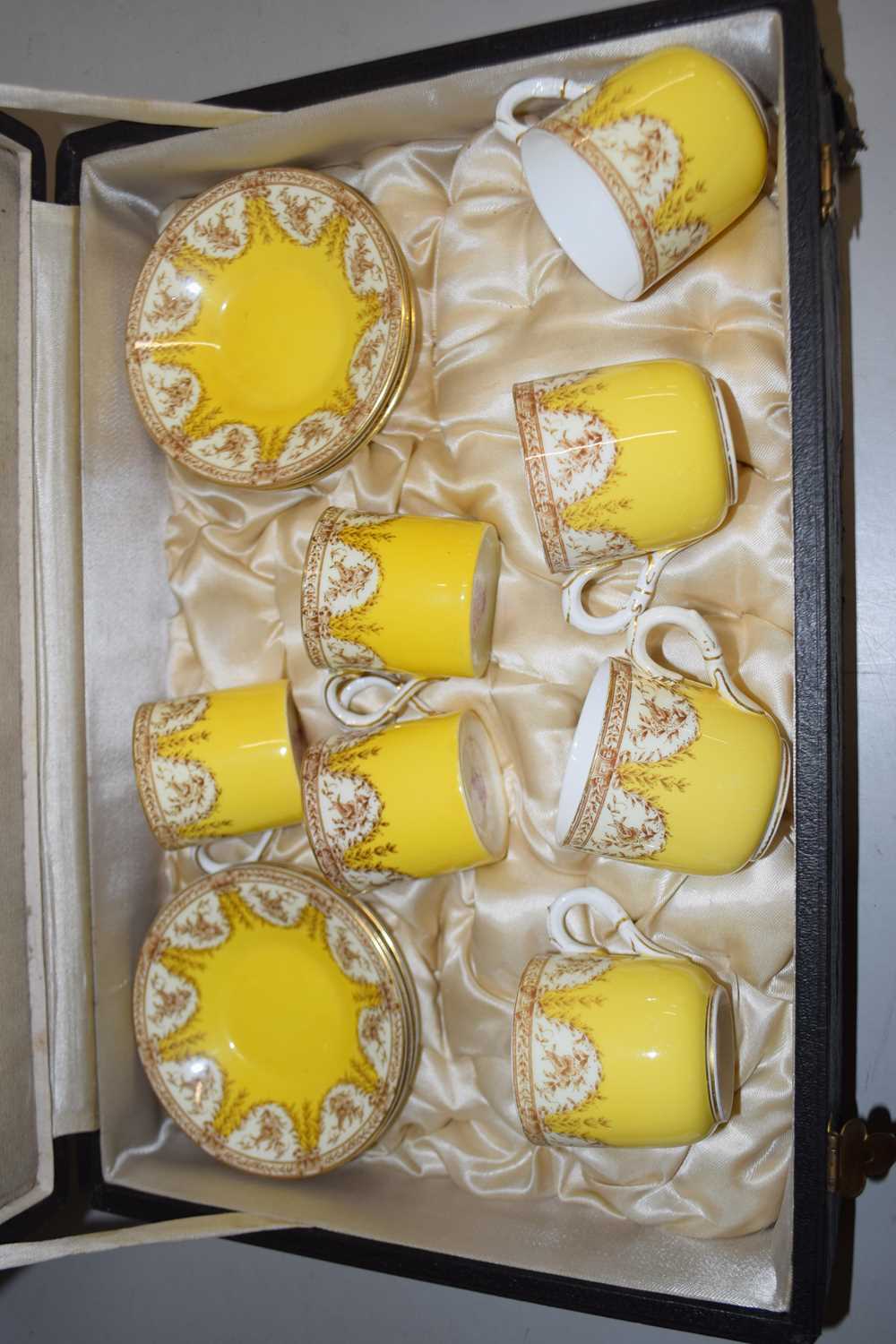 A cased Royal Worcester coffee set, the yellow ground with floral decoration comprising four cups