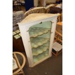 A painted open front wall mounted corner cabinet