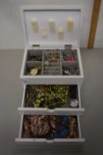 Small white table top cabinet filled with costume jewellery