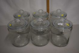 A group of six clear glass kitchen storage jars