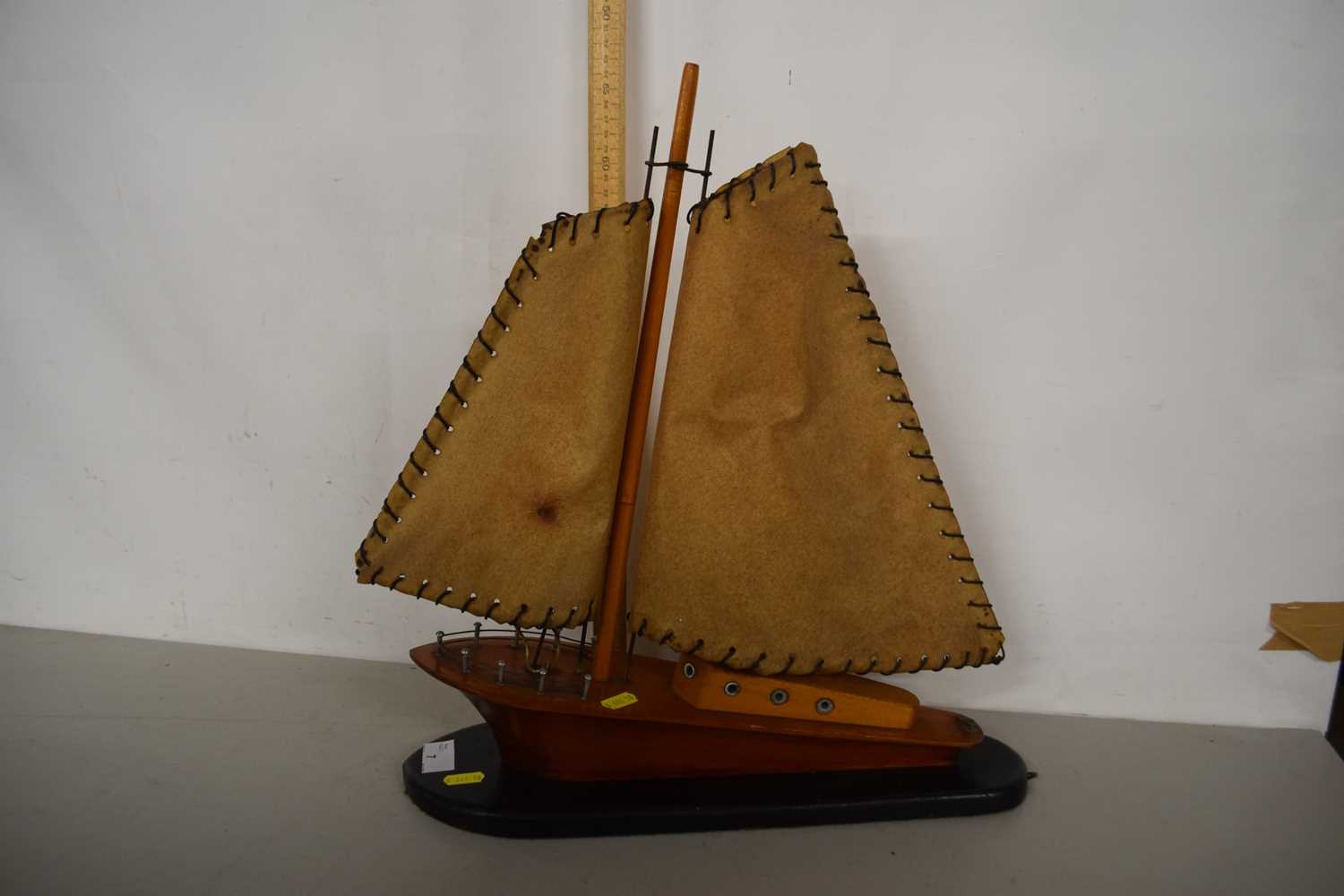 A wooden model of a yacht on black oval plinth