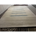 A contemporary cream rug, with blue striped pattern to centre. (some minor wear