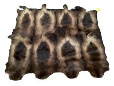 A rug/throw of fur/animal skins, backed on a green felt backing