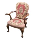 A walnut framed chair with tapestry upholstery, and scrolling arms with carved bird finials,