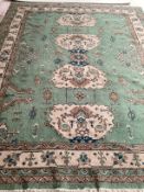 A Turkish style wool rug, central cream medallion on green ground with floral and geometric borders.