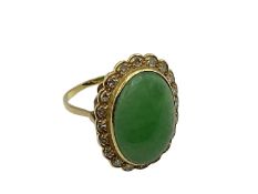 An unmarked yellow metal jade and diamond dress ring, central oval jade cabochon with a surround