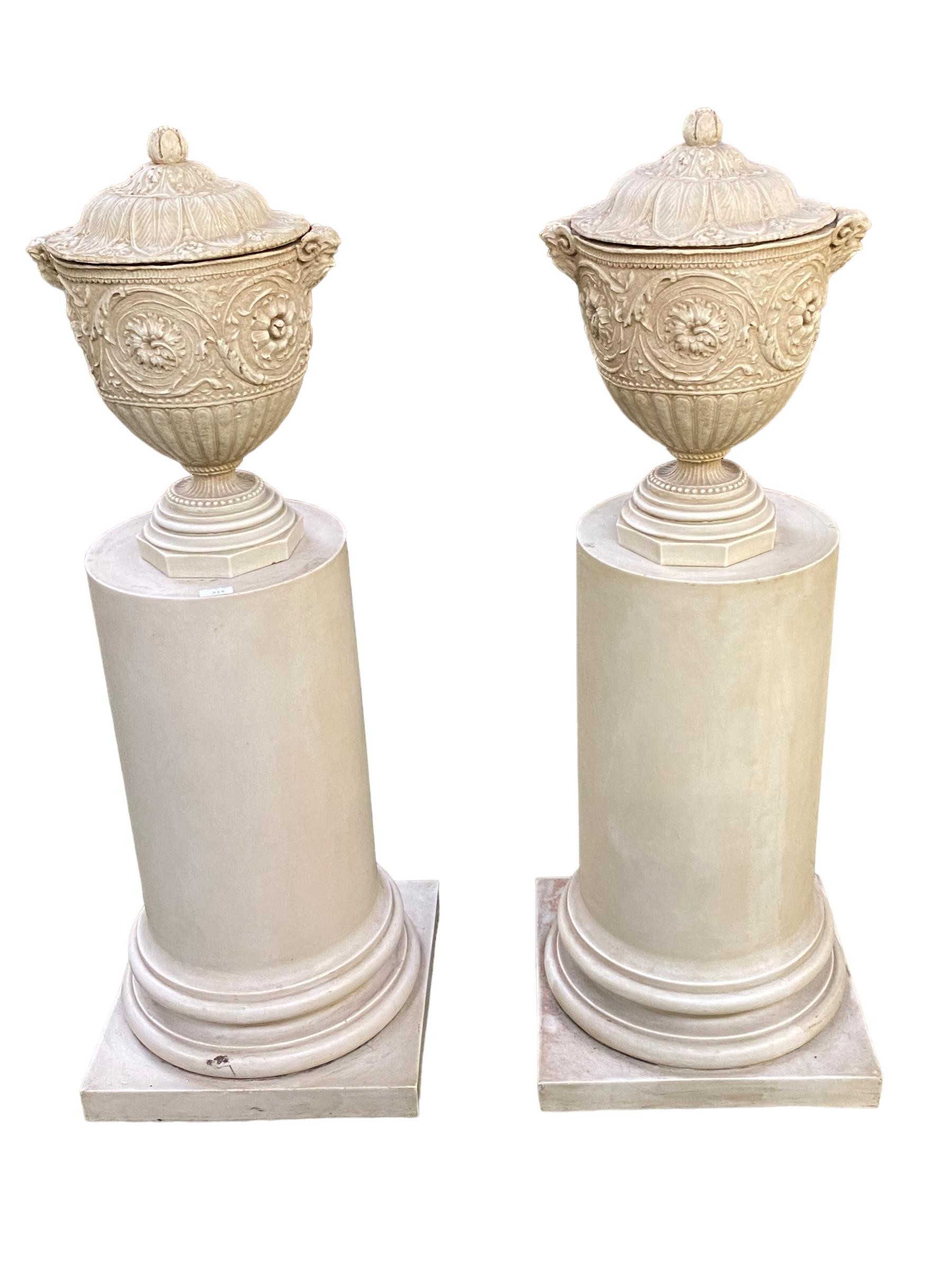 Pair of decorative pedestals, surmounted with lidded urns with satyr masks on composite half