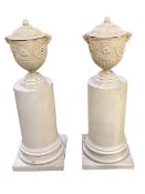 Pair of decorative pedestals, surmounted with lidded urns with satyr masks on composite half