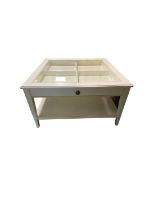 A modern, white/cream, square shaped two tier coffee table with 4 inset panels, no obvious sign of