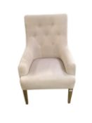 A modern cream upholstered button back chair, raised on wooden feet, some areas of wear/marks