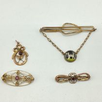 Two unmarked yellow metal brooches together with an unmarked yellow metal pendant and a tie pin .