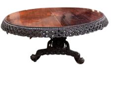 A C19th carved Indian blackwood round pedestal table with pierced foliate frieze, the base carved