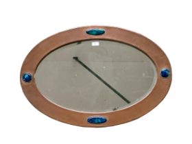 An Arts and Crafts style oval copper mirror, with inset blue stones, 77.5cm Wide overall