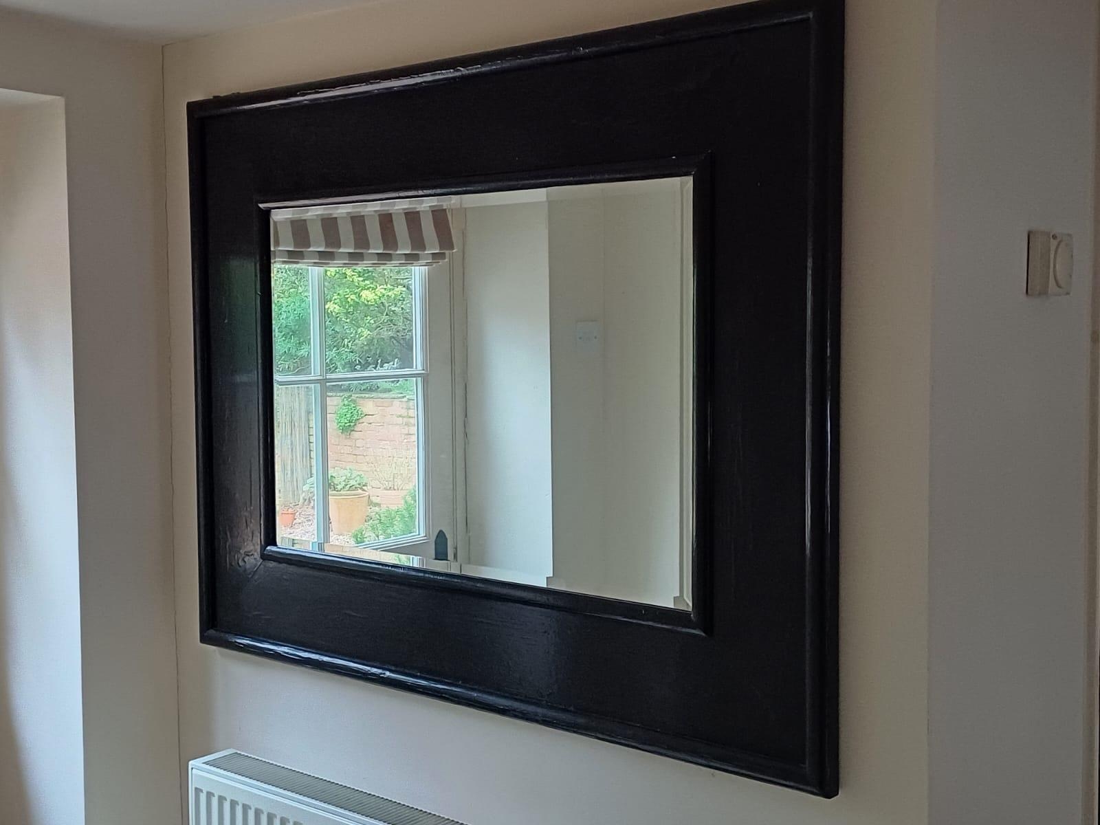 A decorative hanging wall mirror, in ornate scrolling cream frame, 121cmH x 80cmw; and a dark framed