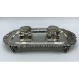 A sterling silver pen tray and ink well with cast border on acanthus leaf supports. With original