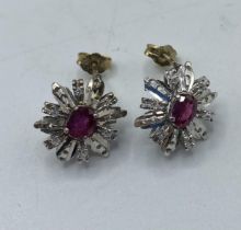A pair of unmarked yellow and white metal earrings set with single oval free cut ruby with a