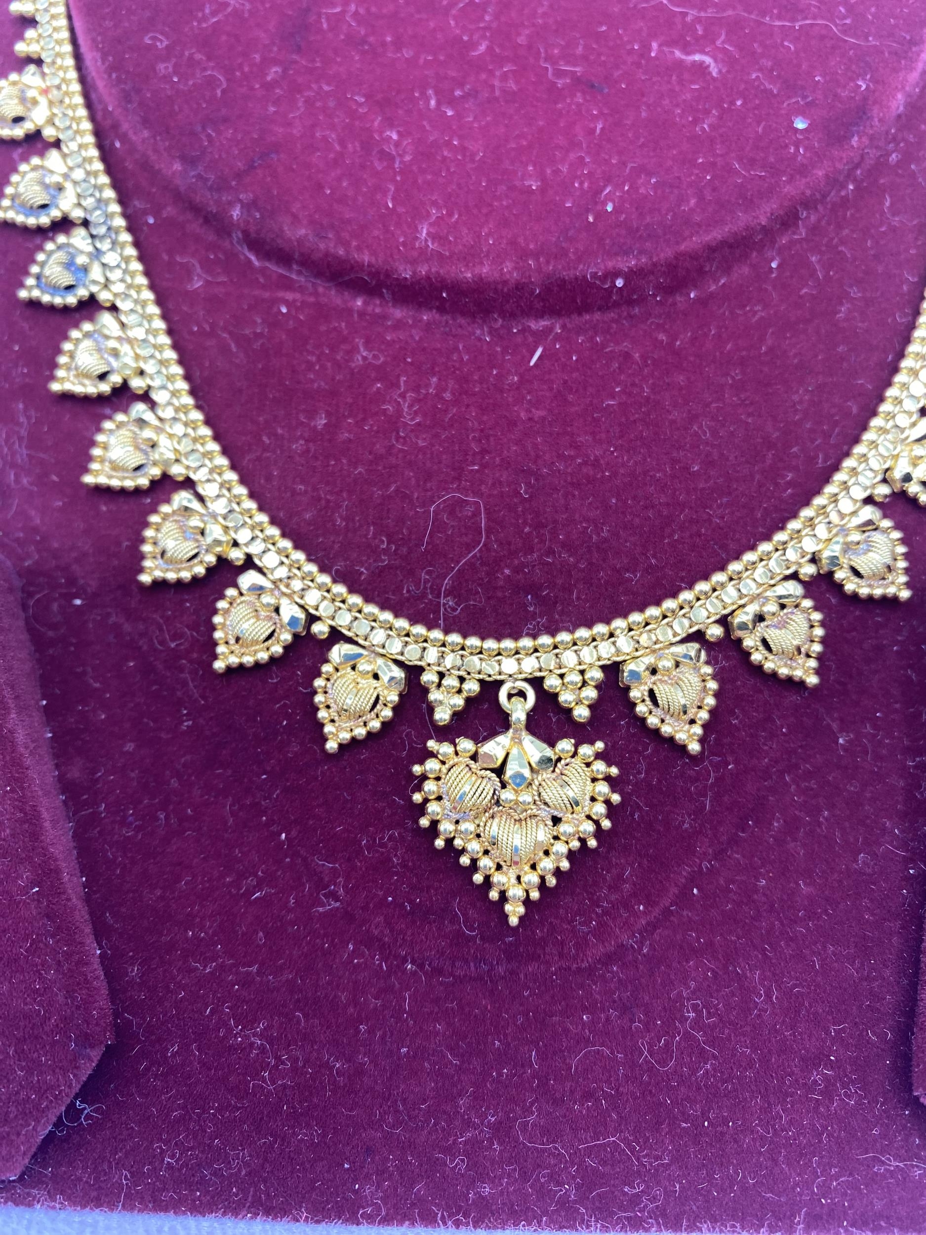 A South Asian unmarked yellow metal necklace with matching earrings marked 88. 21.6g. - Image 2 of 4