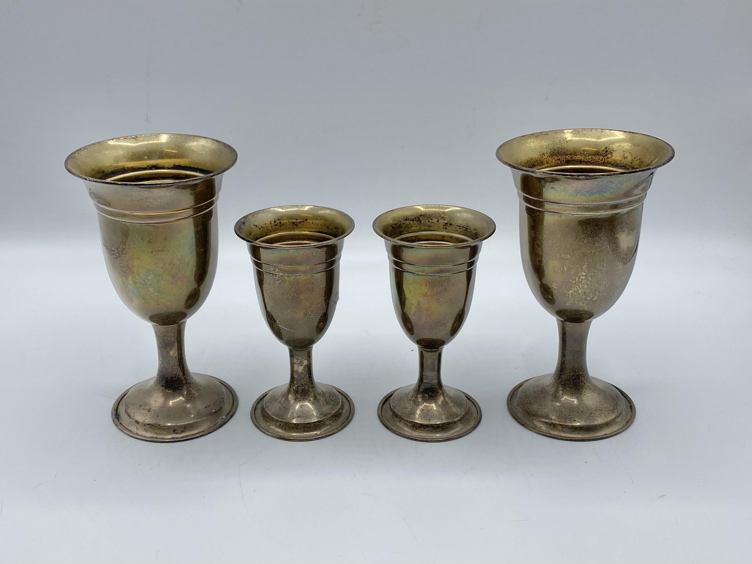 A pair of sterling silver goblets together with a smaller pair of matching silver goblets by W I