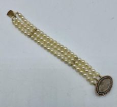 A triple strand pearl bracelet with yellow metal pearl set mourning clasp. 18cm