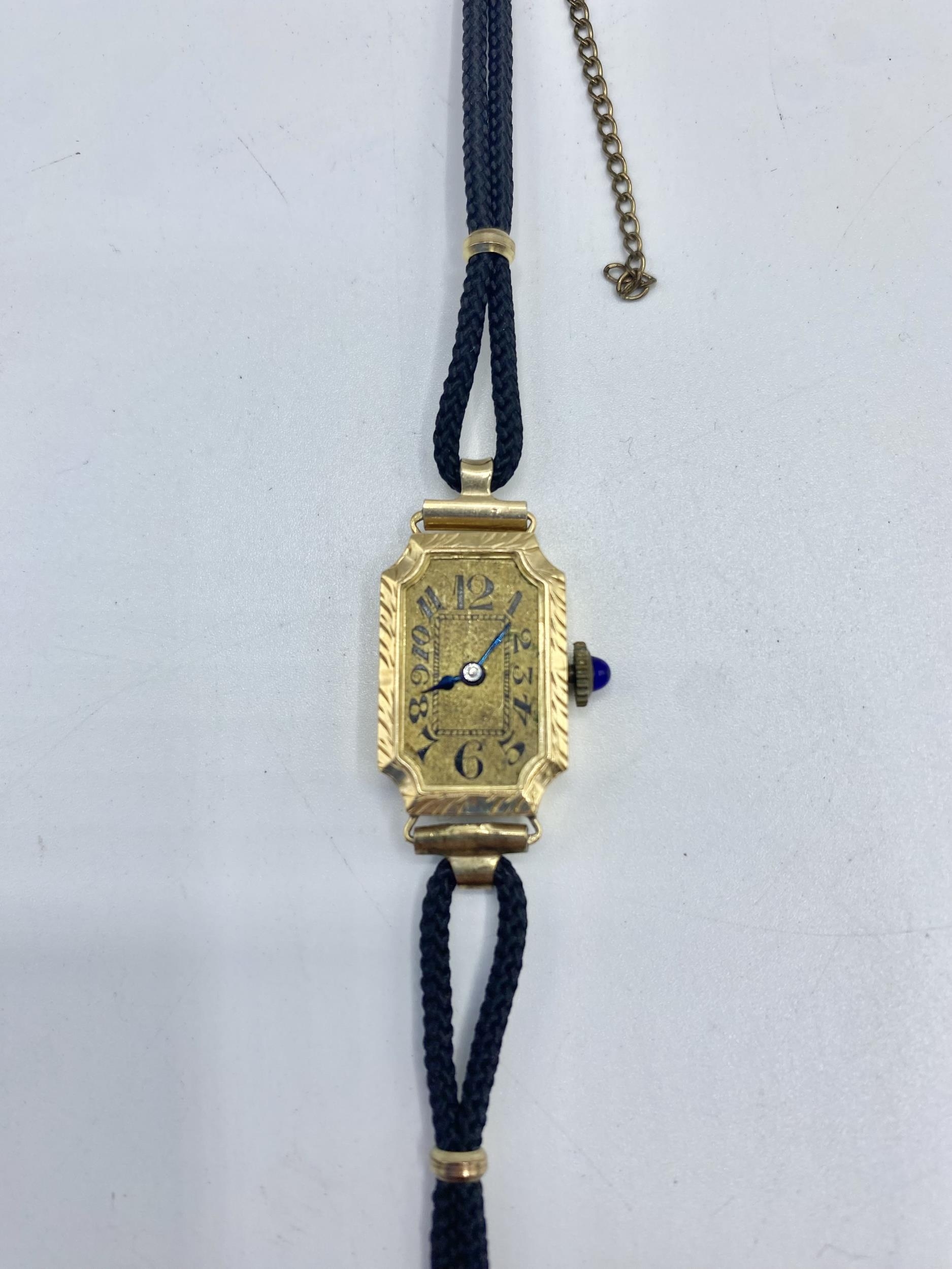 An 18ct gold ladies rectangular cased cocktail watch blue cabochon crown. gold face with roman