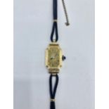 An 18ct gold ladies rectangular cased cocktail watch blue cabochon crown. gold face with roman