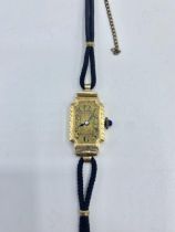 An 18ct gold ladies rectangular cased cocktail watch blue cabochon crown. gold face with roman