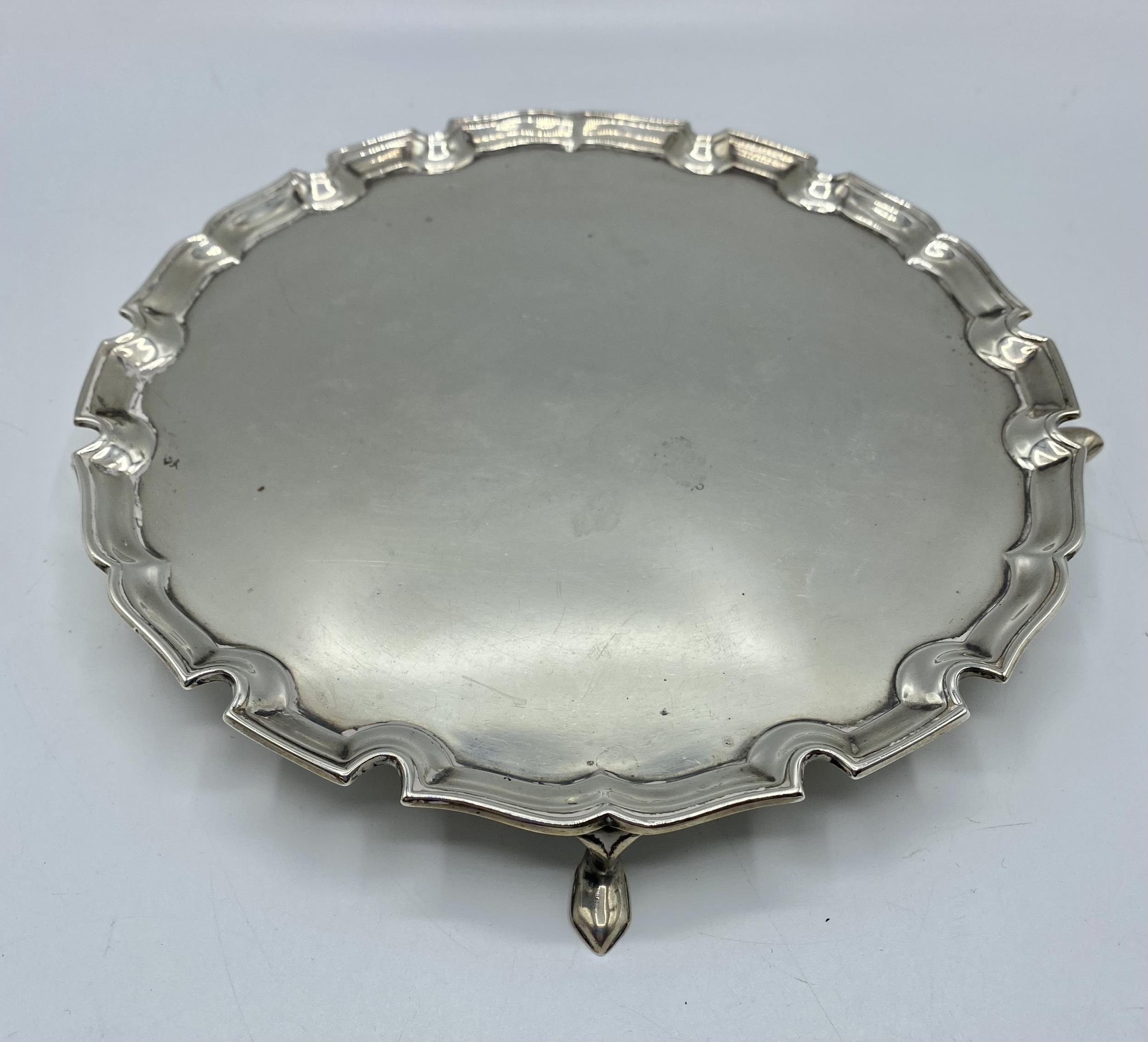 A sterling silver circular card tray with cast border on three feet. 21cm(d) by Edward Barnard &