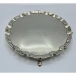 A sterling silver circular card tray with cast border on three feet. 21cm(d) by Edward Barnard &